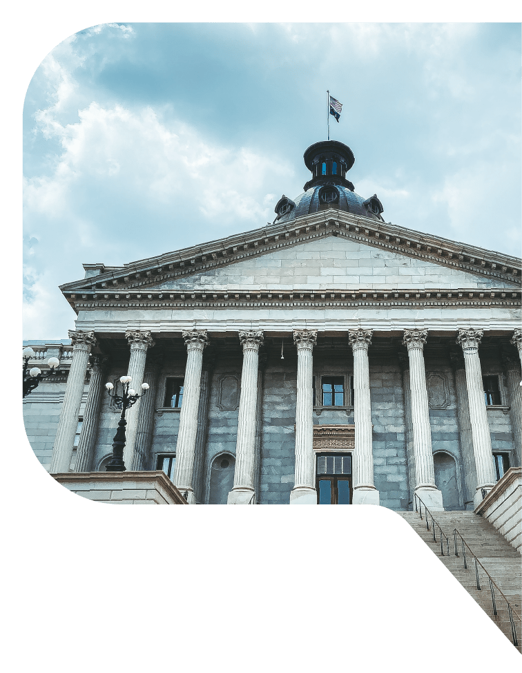 View looking up the stairs at the marble columns and flag-topped cupola of City Hall in Columbia, South Carolina.